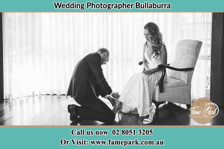 The Bride is being helped by the Groom trying to put on her shoes Bullaburra NSW 2784